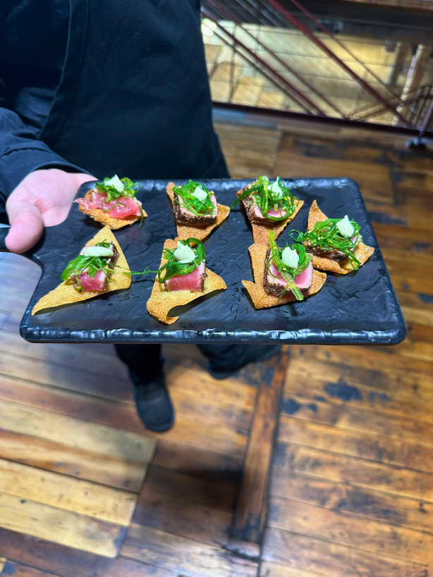 Seared tuna on wonton nachos, a passed appetizer presented by a catering server.