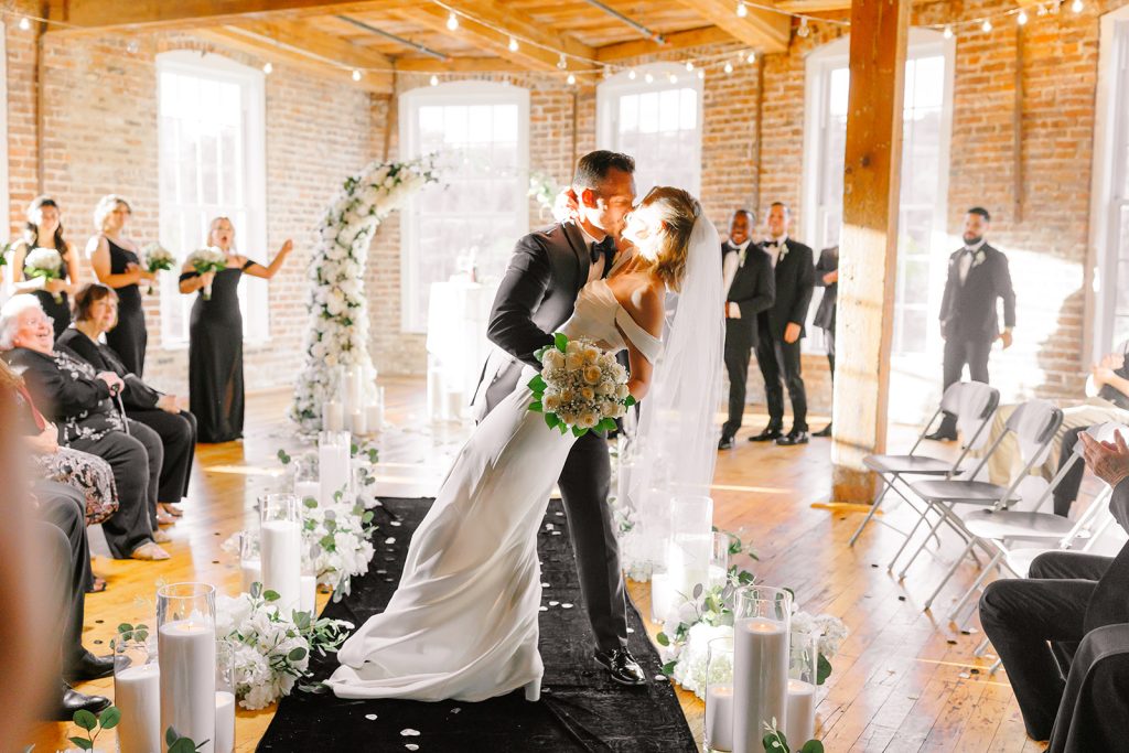 Bride is dipped into a kiss by her groom, in the River Overlook of the Power House at Rocky Mount Mills, following their wedding ceremony.