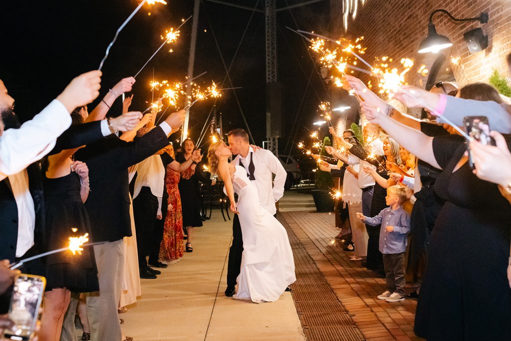 Bride and groom share a kiss outside the Power House, as guests cheer them on with sparklers.